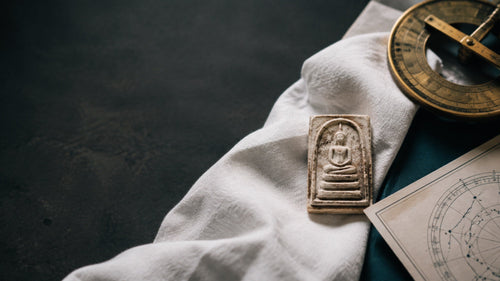 Illustrative still life of an amulet and working materials. Not a client result.